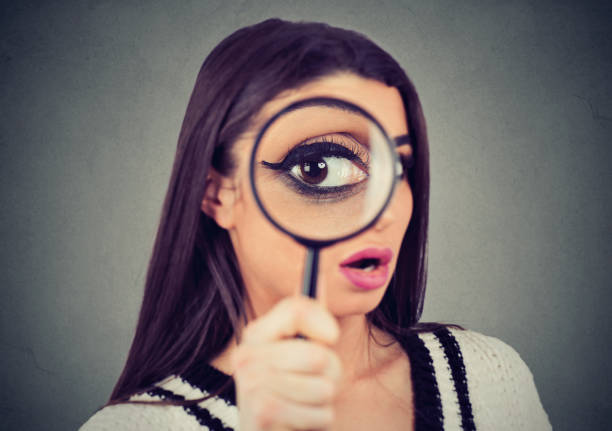 istock Curious woman looking through a magnifying glass 1125799113