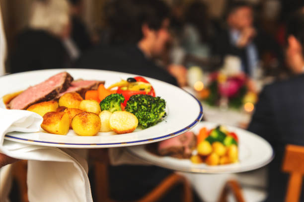 istock Waiter carrying two plates with meat dish on some festive event, party, wedding reception or catered event 1125801247