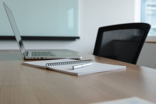 istock Pen on notepad and laptop and for agenda kept on table in empty corporate conference room. selected focus on pen and notepad. 1125801441