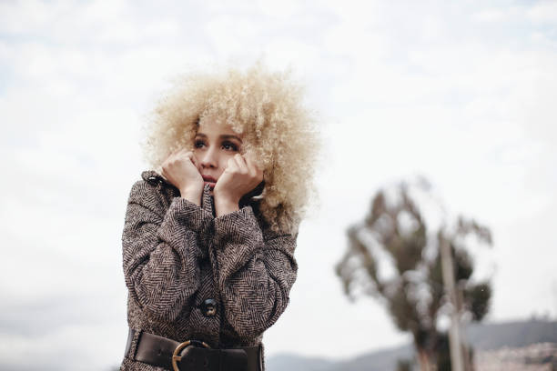 Woman between 20 - 35 years old with a jacket and crossed arms protected from the cold climate of the city