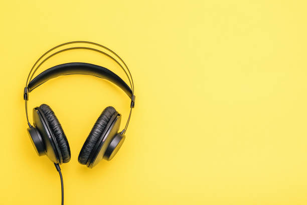 istock Black headphones with wires on a yellow background. 1125807565