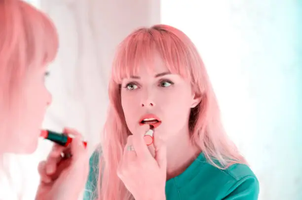 Reflection of girl applying lipstick