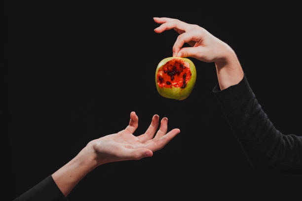 istock Woman passes a bitten blood apple into a man's hand 1125812658