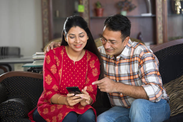 Amazed couple watching online content on mobile phone Surprised young couple watching online content on mobile phone happy husband and wife india stock pictures, royalty-free photos & images