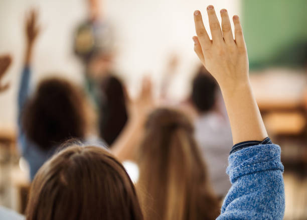 istock Back view of female student raising hand on a class. 1125837261