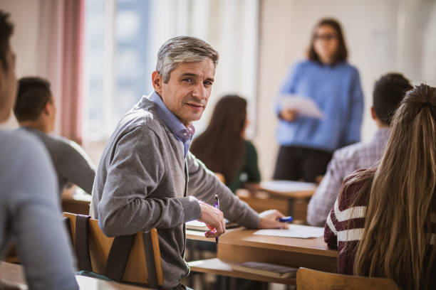 istock Mid adult teacher among his students on a class at school. 1125837591