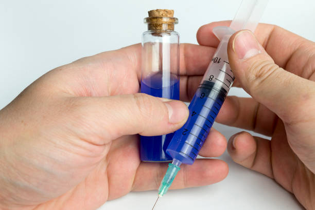 istock Hand holding test tube with blue liquid and a syringe. 1125839200