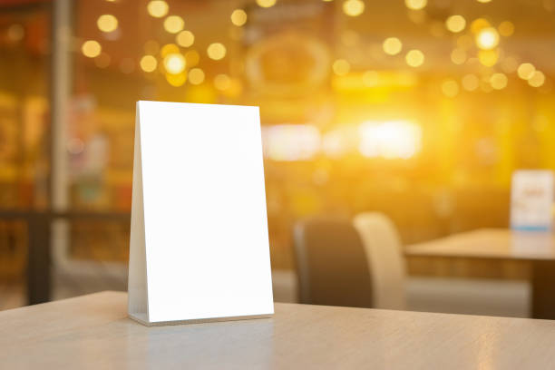 istock Mock up Label the blank menu frame in Bar restaurant ,Stand for booklets with white sheets paper acrylic tent card on wooden table cafeteria blurred background can inserting the text of the customer. 1125840212