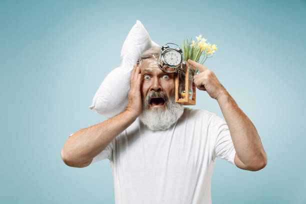 istock Tired man sleeping at home having too much work. Bored businessman with pillow and hourglass 1125840921