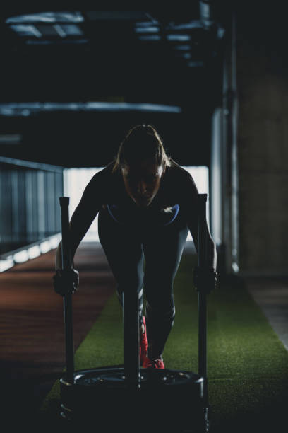 istock Woman doing sled training in a dark gym 1125842077