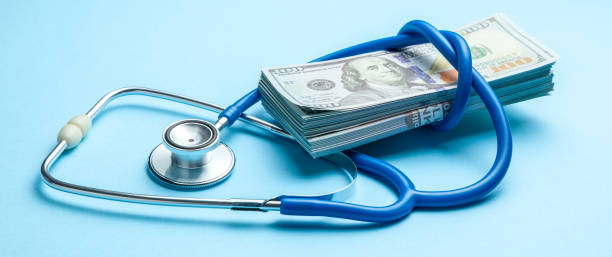 pila di dollari in contanti e stetoscopio su sfondo blu. il concetto di strechevka medica o medicina costosa, stipendio dei medici - currency stethoscope healthcare and medicine savings foto e immagini stock