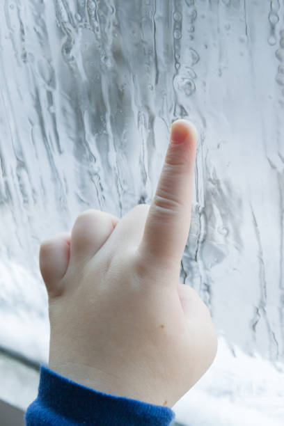 istock The child's hand draws patterns on the frozen window in winter 1125843187
