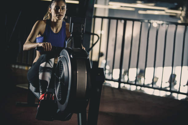istock Young woman exercising on rowing machine 1125843453