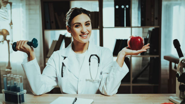 istock Female Doctor is Holding Apple and Dumbbell 1125844469