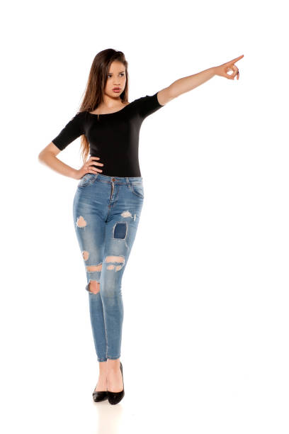 istock A young girl in a ripped jeans pointing on a white background 1125844541