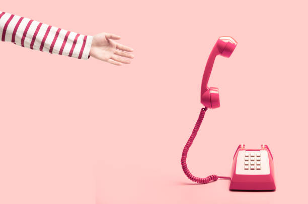 手はピンクのレトロな電話、ピンクの背景、ピンクの背景に浮かぶ携帯電話電話に手を差し伸べるします。販売や契約の概念 - vintage telephone ストックフォトと画像