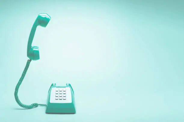 Retro green telephone on teal green background, Pop art or retro style.