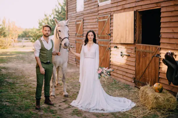 boho style newlyweds standing near horse