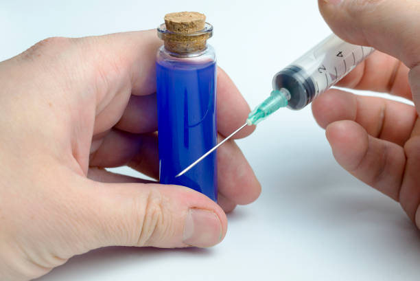 istock Hand holding test tube with blue liquid and a syringe. 1125854837