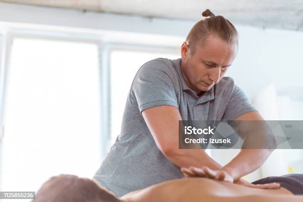 Physiotherapist Massaging Mens Back Stock Photo - Download Image Now - Adult, Adults Only, Alternative Therapy