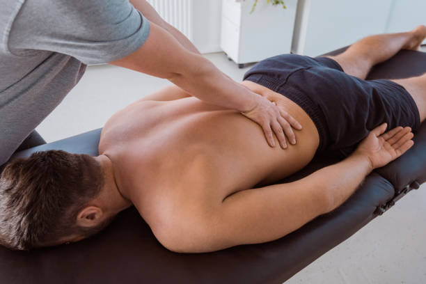 fisioterapista massaggia la parte posteriore dell'uomo - human spine chiropractic adjustment back pain foto e immagini stock