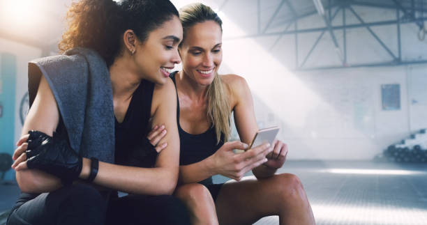 mantendo-se com o mais recente, em qualquer lugar, a qualquer momento - friendship women exercising gym - fotografias e filmes do acervo