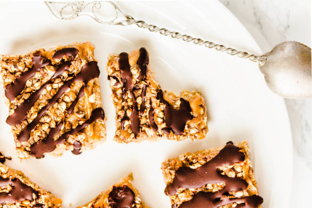 Granola bar with date caramel and chocolate. Healthy sweet dessert snack. Cereal granola bar with nuts, fruit and berries on a white marble table. A cup of coffee.Healthy breakfast. stock photo