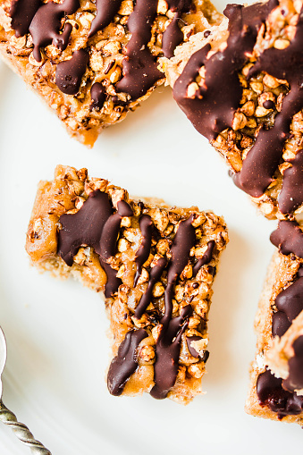 istock Granola bar with date caramel and chocolate. Healthy sweet dessert snack. Cereal granola bar with nuts, fruit and berries on a white marble table. A cup of coffee.Healthy breakfast. 1125868144