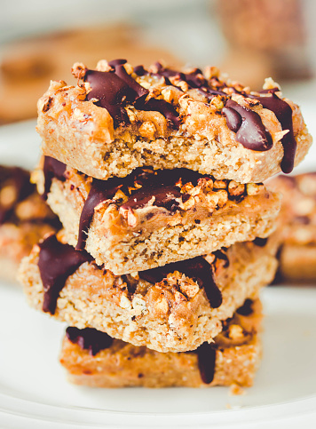 istock Granola bar with date caramel and chocolate. Healthy sweet dessert snack. Cereal granola bar with nuts, fruit and berries on a white marble table. A cup of coffee.Healthy breakfast. 1125868160