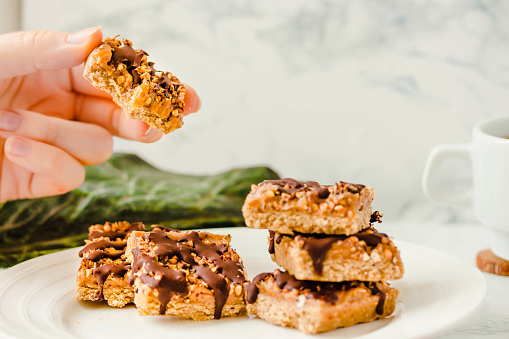 istock Granola bar with date caramel and chocolate. Healthy sweet dessert snack. Cereal granola bar with nuts, fruit and berries on a white marble table. A cup of coffee.Healthy breakfast. 1125868166