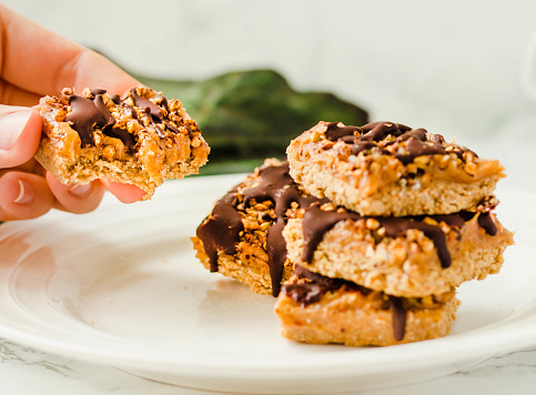 istock Granola bar with date caramel and chocolate. Healthy sweet dessert snack. Cereal granola bar with nuts, fruit and berries on a white marble table. A cup of coffee.Healthy breakfast. 1125868167