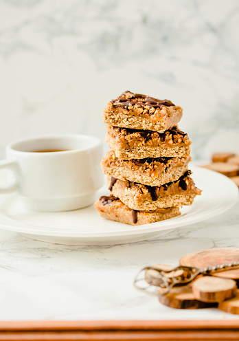 istock Granola bar with date caramel and chocolate. Healthy sweet dessert snack. Cereal granola bar with nuts, fruit and berries on a white marble table. A cup of coffee.Healthy breakfast. 1125868219