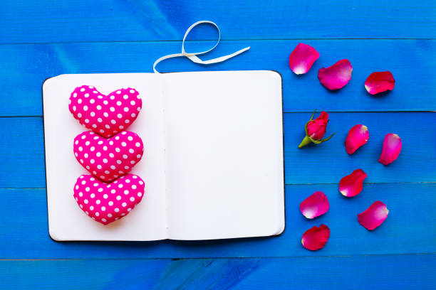 istock Diary notebook with rose and valentine's hearts on blue wooden background. 1125868253