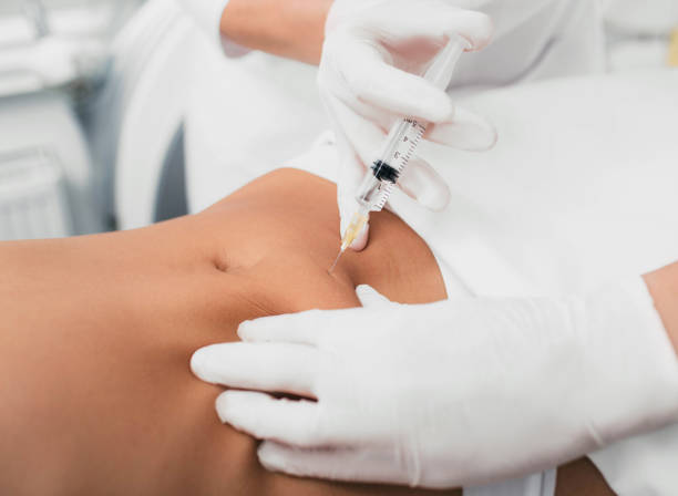 woman getting an injection in her tummy close-up Injection into female belly, body mesotherapy. Beautician removing cellulite on the abdomen using beauty injections. east slavs stock pictures, royalty-free photos & images
