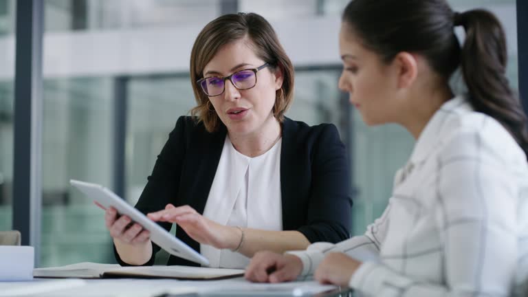 4k video footage of two businesswomen working together on a digital tablet in an office