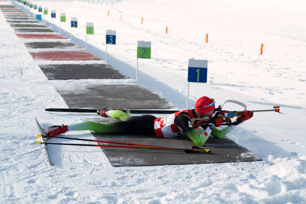 젊은 남성 바이애슬론 경쟁자 연습 촬영, 거짓말 위치 대상의 측면 보기 - biathlon 뉴스 사진 이미지