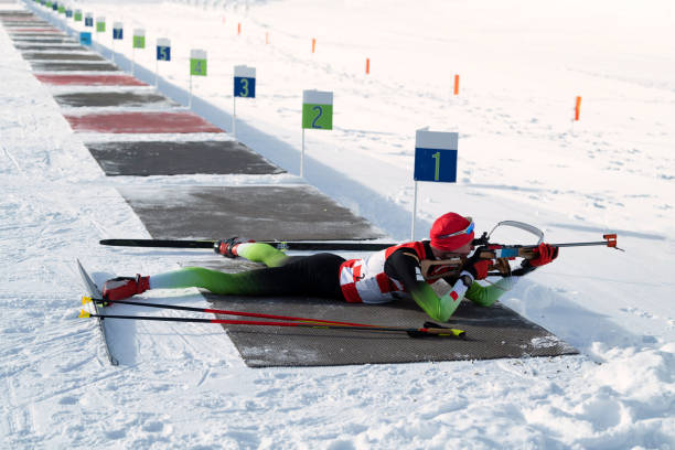 side view of young male biathlon competitor practicing target shooting, lying position - biathlon imagens e fotografias de stock