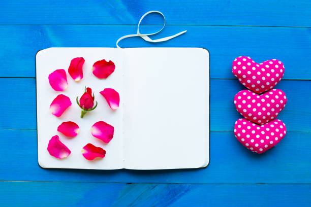 istock Diary notebook with rose and valentine's hearts on blue wooden background. 1125873182
