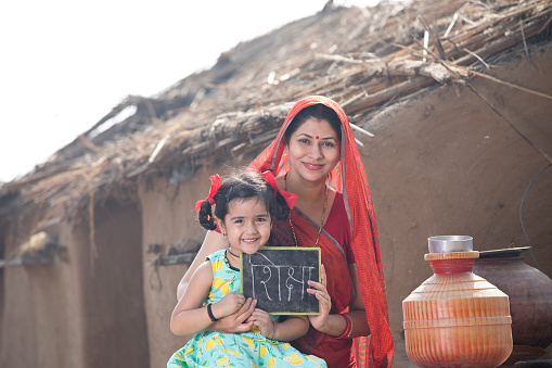 Mother with her daughter holding slate at village