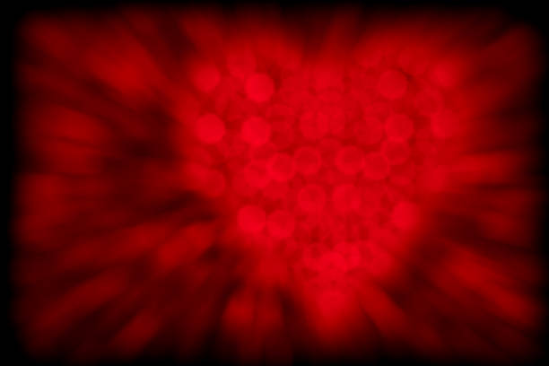 Heart made of red defocused lights on a dark background. Beautiful bokeh with motion blur effect.