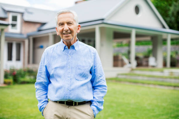 istock Senior man with hands in pockets against house 1125875027
