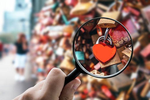 A magnifying glass over a heart-shaped padlock