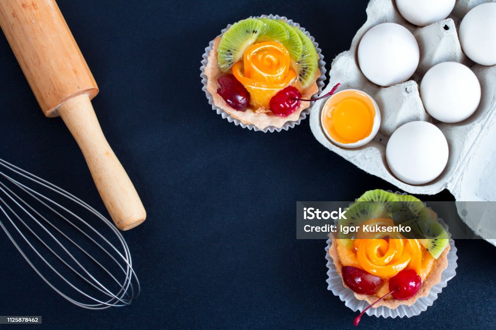 ケーキ、麺棒とテーブルに泡立て器とトレイの卵 - まな板のロイヤリティフリーストックフォト