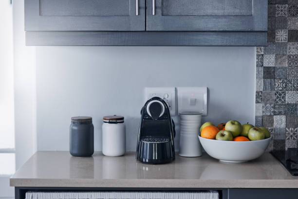 Ready for the morning Shot of a kettle, condiments and a bowl of fruit on a kitchen counter coffee maker in kitchen stock pictures, royalty-free photos & images