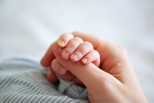 bébé garçon tenant la main de mères - baby newborn human hand mother photos et images de collection