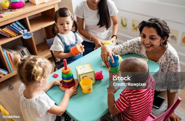 Bambini In Asilo Che Giocano Con Linsegnante In Classe - Fotografie stock e altre immagini di Servizi per l'infanzia