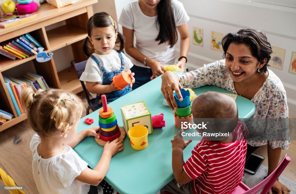 Nursery children playing with teacher in the classroom Child Care Stock Photo