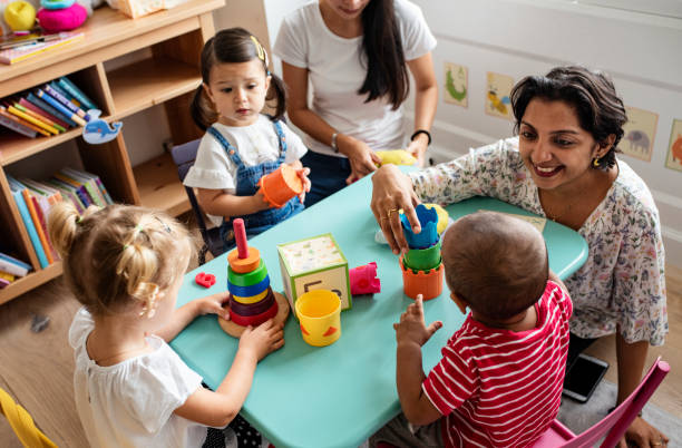 Nursery children playing with teacher in the classroom Nursery children playing with teacher in the classroom toddlers playing stock pictures, royalty-free photos & images