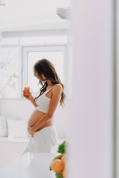 istock Pretty future mom looking at belly and holding juice in hand 1125881973