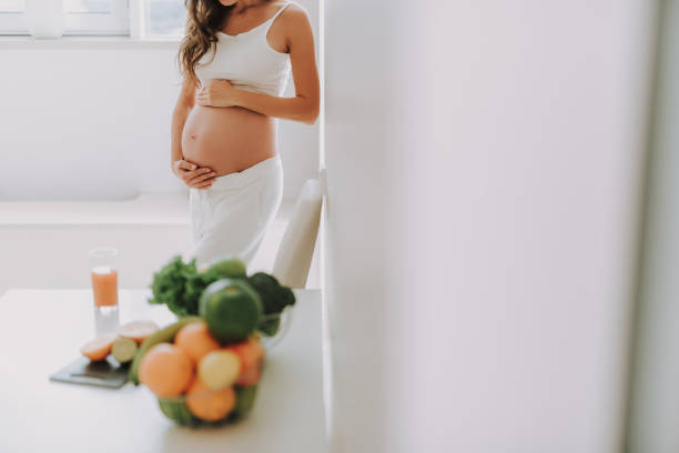 istock Future mum holding hands on belly and standing in kitchen 1125882002